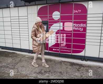 Loriol sur Drome, Frankreich - 14. Januar 2023: Abholung eines Pakets aus einem Mondial`Relay-Schließfach durch eine junge Frau. Schließfächer Mondial Relay. Pickup-Box. Stockfoto